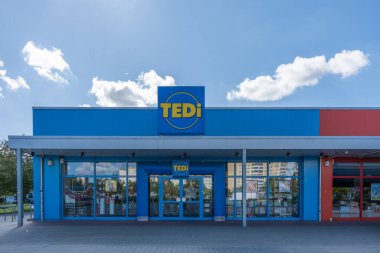 Almanya 7 Eylül 2025. Mavi binalı bir TEDi mağazasının ön görüntüsü. Camlar güneşli gökyüzünü yansıtıyor..