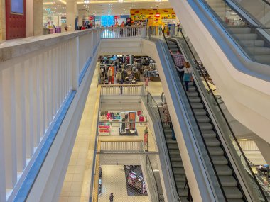 Almanya Berlin 09.13.2025. Alışveriş merkezinin içinde yürüyen merdivenler var. Farklı katlarda yürüyen merdivenleri, korkulukları ve giyim mağazaları olan canlı bir alışveriş merkezi. İnsanlar içeride alışveriş yapıyor..