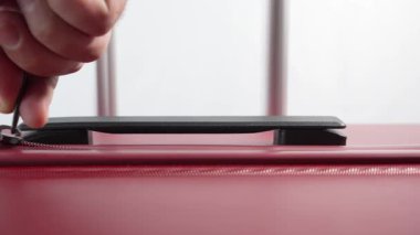 Yakından çekilmiş bir video kırmızı bir bavula tek bir fermuar çeken bir eli gösteriyor. Bagajın sorunsuz bir şekilde açılıp kapanması üzerinde duruluyor..