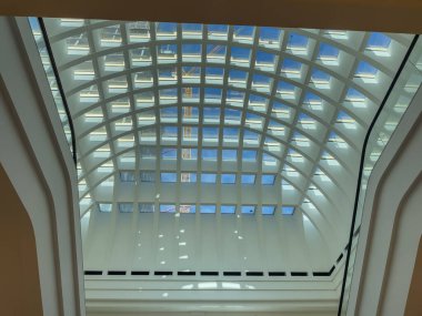 Geometrik ızgaralı modern cam çatı binaya bolca gün ışığı girmesini sağlıyor. Gökyüzü manzaralı zarif mimari detay.