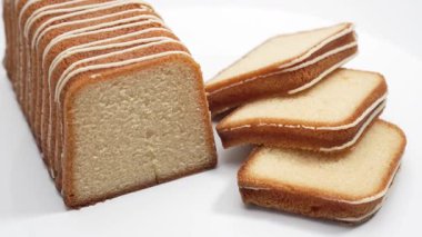 Yanında dilimler olan bir somun kek döner. Işıl ışıl iç kısım, altın kabukla çelişiyor..