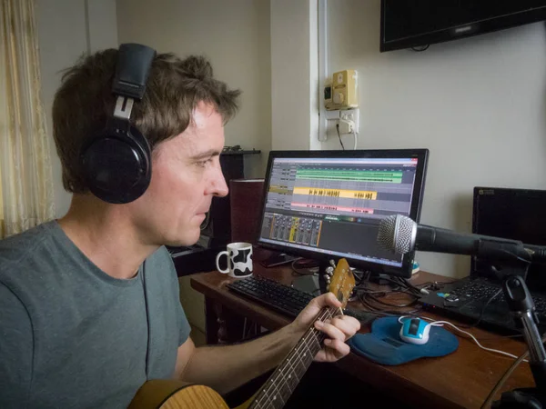 Medium view bağımsız müzisyen evde onun dijital ses iş istasyonu içine akustik gitar ve vokal kayıtları. Teknolojideki mevcut trendler, giderek daha fazla üreticinin evde ucuza kayıt kaydetmesine olanak sağlıyor. 