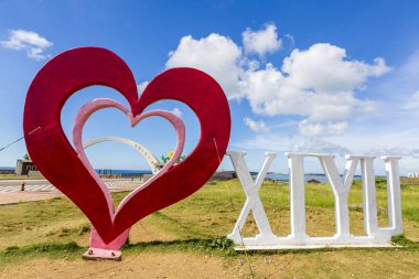 mavi bulutlu gökyüzü altında çim üzerinde aşk xixyu heykel