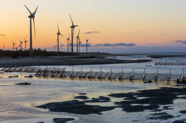 gün batımında denizde elektrikli yel değirmenleri ve balıkçılık ağları
