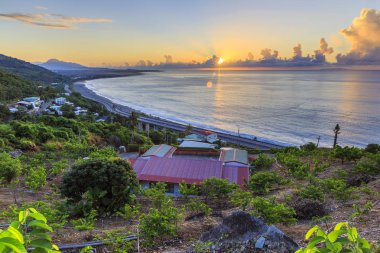 akşam okyanus kıyısında evler ile yeşil tepe