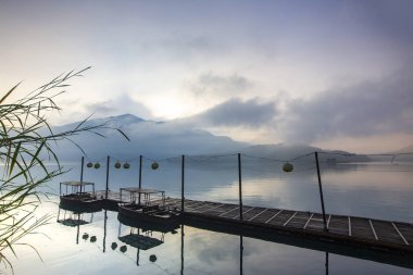 rıhtım da demirlemiş tekneler ve bulutlu gökyüzü suya yansıyor