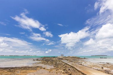 bulutlu gökyüzü altında okyanus tarafından uzak küçük bina