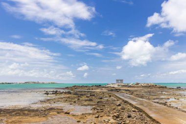 bulutlu gökyüzü altında okyanus tarafından uzak küçük bina