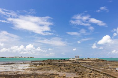 bulutlu gökyüzü altında okyanus tarafından uzak küçük bina