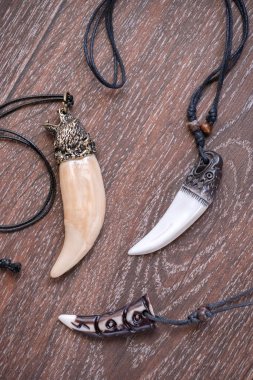 Sibirya geyik kahverengi bir arka plan üzerinde gelen büyük ayı diş ve kemik kolye oyulmuş