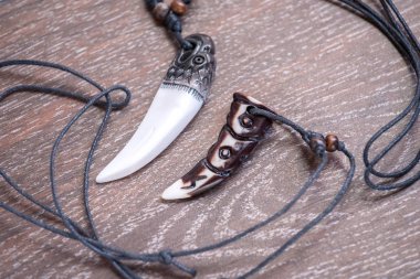 Sibirya geyik kahverengi bir arka plan üzerinde gelen büyük ayı diş ve kemik kolye oyulmuş