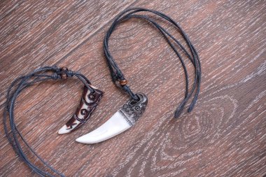 Sibirya geyik kahverengi bir arka plan üzerinde gelen büyük ayı diş ve kemik kolye oyulmuş