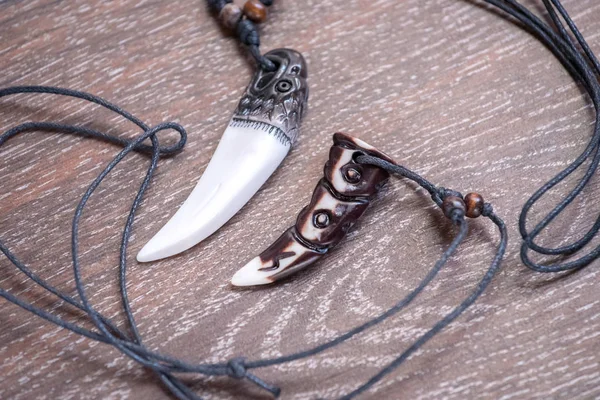 Sibirya geyik kahverengi bir arka plan üzerinde gelen büyük ayı diş ve kemik kolye oyulmuş