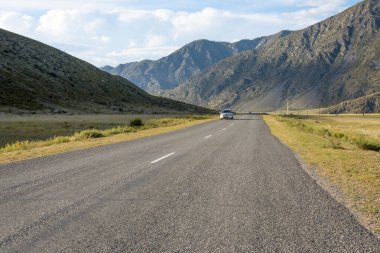 Yaz ve mavi gökyüzü bulutlu dağlık alanda dolambaçlı yol asfalt