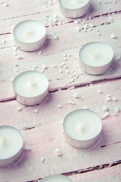 A few flat white candles on a beautiful wooden pink table