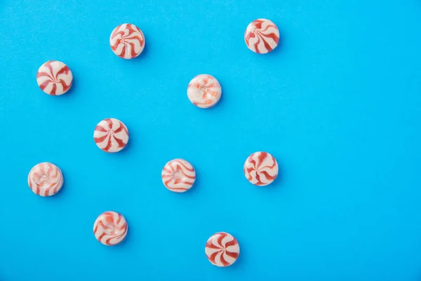 Round candy caramel red and white on a blue background