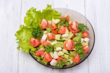 Taze sebze, şalgam, salatalık, domates, beyaz zemin üzerine maydanoz ve avokado lezzetli salata