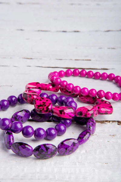 Several Beautiful Bracelets Beads Stones Pink Purple White Wooden Background — Stock Photo, Image