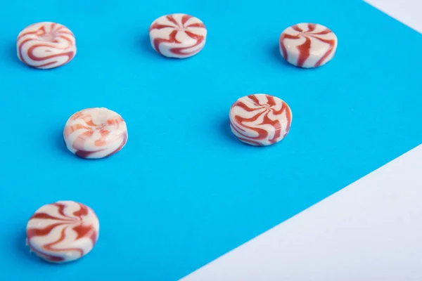 Round candy caramel red and white on a blue background