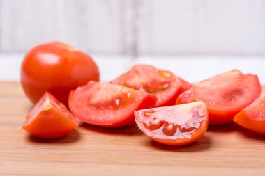 Beyaz zemin üzerinde bir ahşap tahta üzerinde sulu olgun kırmızı domates doğranmış