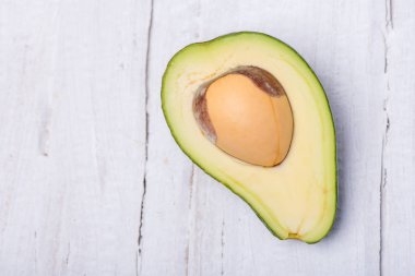Beyaz zemin üzerinde bir ahşap tahta üzerinde sulu olgun yeşil avokado doğranmış