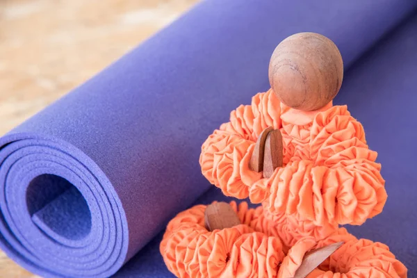 Figurine in orange clothes sitting in a yoga pose with a purple mat for exercise and meditation