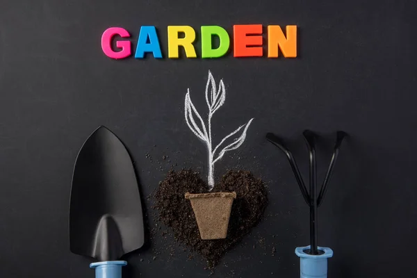 Seedling drawn in chalk with earth on black board as background for season of garden