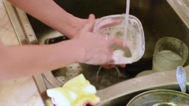 Kadın evde bulaşıkları yıkıyor.