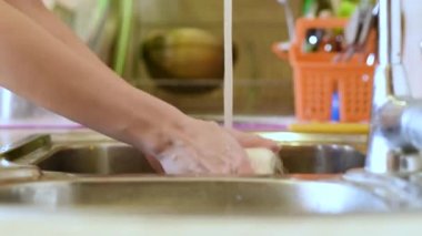 Kadın evde bulaşıkları yıkıyor.