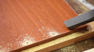 Kahverengi tahtadaki matkap deliğinden odun talaşlarını süpürüyorum.