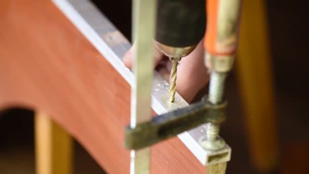 男は家具を組み立てるために木製の茶色の板に穴を開ける — ストック動画