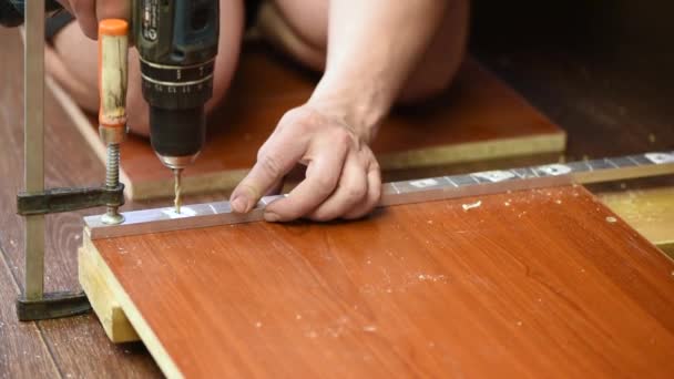 一个人在木制的棕色木板上打孔以组装家具 — 图库视频影像