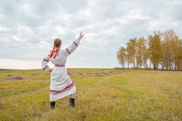 Девушка в славянском платье с красной лентой в волосах стоит — стоковое фото