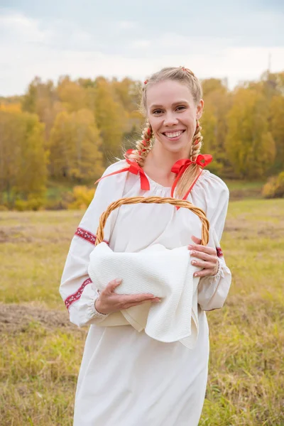 Menina bonita em um vestido eslavo tradicional com uma cesta de palha — Fotografia de Stock