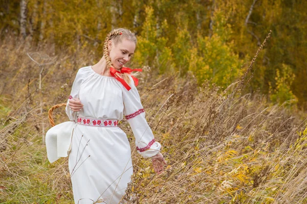 Krásná dívka v tradičních slovanských šatech se slamným košíkem — Stock fotografie