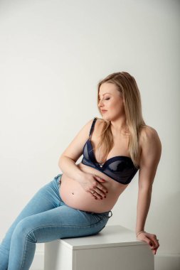 Mavi kot güzel hamile kadın sarışın Whit üzerinde göbek hugs