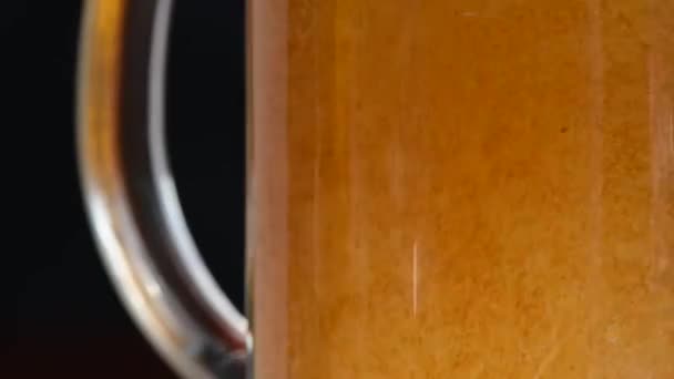 在一个大玻璃杯里倒入了金色的啤酒 在黑色的背景上有泡沫 — 图库视频影像