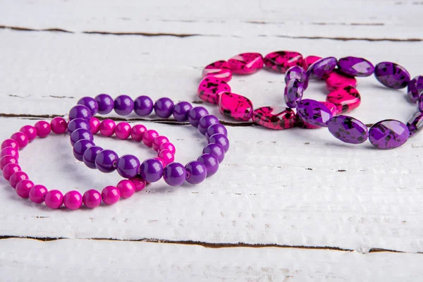 Several beautiful bracelets of beads and stones of pink and purp — Stock Photo, Image
