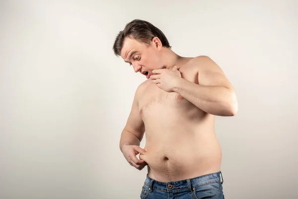Un hombre en jeans con vientre gordo y torso desnudo en un bac blanco — Foto de Stock