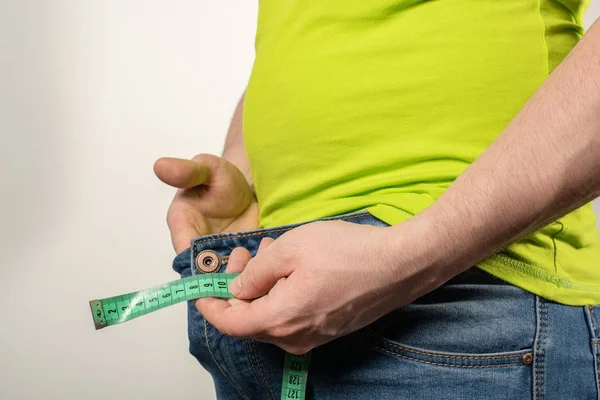 Close up de homem segurando fita métrica perto de jeans com zíper . — Fotografia de Stock