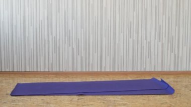 Güzel ince esmer kız paspaslar üzerinde Yoga Ekipmanları atar