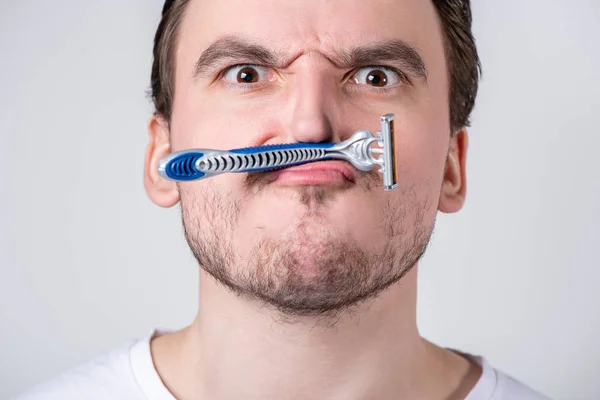 Schöner Mann mit Stoppeln im Gesicht hält ein Rasiermesser in der Hand — Stockfoto