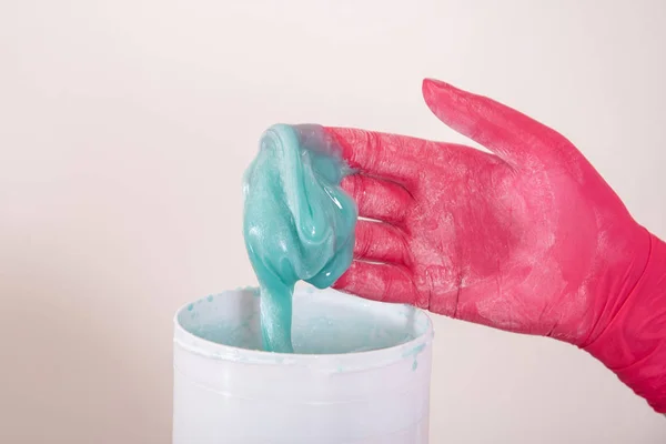 Master in medical gloves holds blue liquid paste for sugar depil