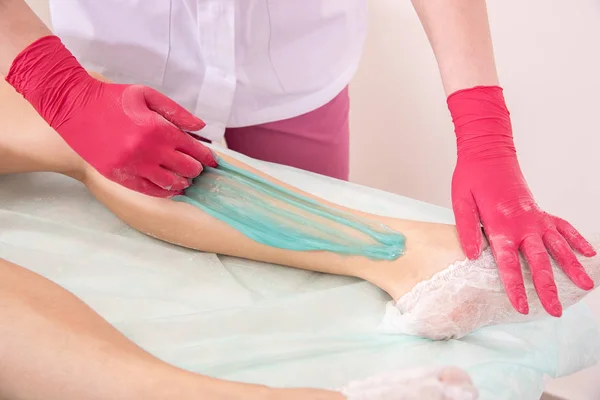 The process of sugar depilation. Master in medical gloves puts a