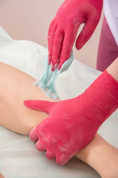 The process of sugar depilation. Master in medical gloves puts a