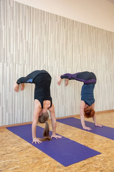 Dos mujeres se paran en las manos contra la pared y practican yoga posan — Foto de Stock