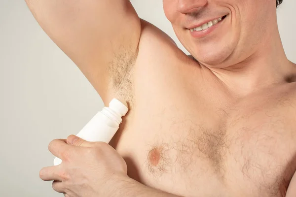 Handsome man with armpits holding a roll-on deodorant in his han — Stock Photo, Image