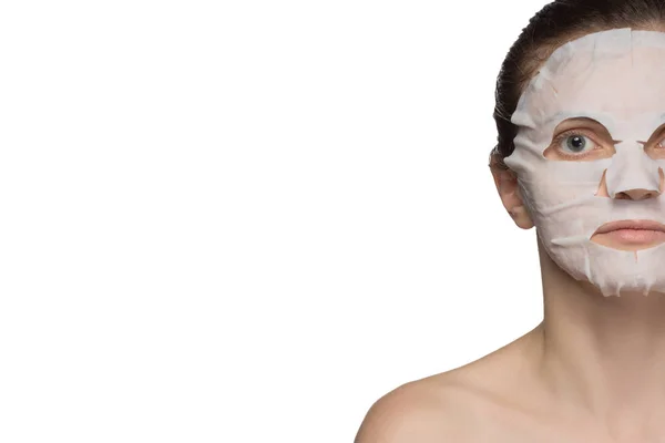 Красивая молодая женщина наносит косметическую маску на лицо — стоковое фото