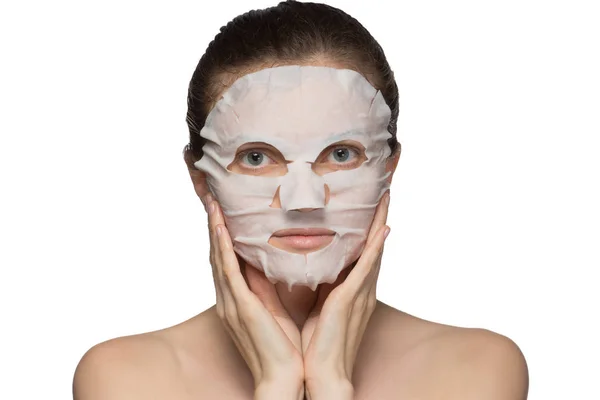 Beautiful young woman is applying a cosmetic mask on a face on a — Stock Photo, Image