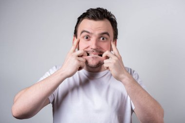 Beyaz bir t-shirt kılları ile Yakışıklı adam komik grimac yapar